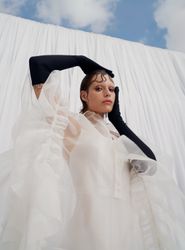 A beautiful pastel white gown with sheer, flowing layers and bold ruffle accents, designed for the avant-garde bride. A sustainable wedding collection designed in Vienna, that redefines modern bridal fashion with its striking, minimalist aesthetic.