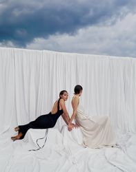 An elegant pastel white or deep black gown with open back and flowing wide straps, designed for the modern bride. A sustainable wedding collection designed in Vienna, that redefines modern bridal fashion with its striking, minimalist aesthetic.