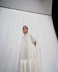 An avant-garde pearl white gown with bold puffy ruffles and short, wide sleeves, designed for the unconventional bride. A sustainable wedding collection designed in Vienna, that redefines modern bridal fashion with its striking, minimalist aesthetic.