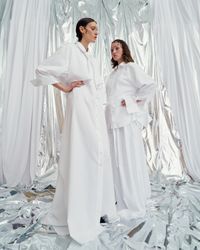 An unconventional pastel white buttoned gown with bow sleeves, designed for the avant-garde bride. A sustainable wedding collection designed in Vienna, that redefines modern bridal fashion with its striking, minimalist aesthetic.